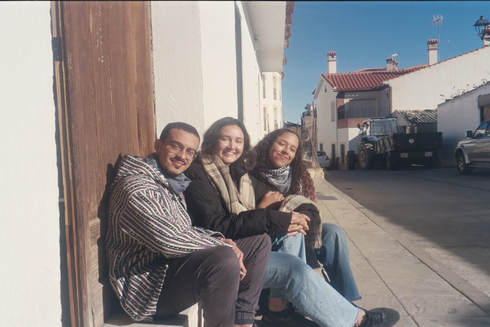 Jóvenes de la comunidad sentados al sol en una calle de pueblo.